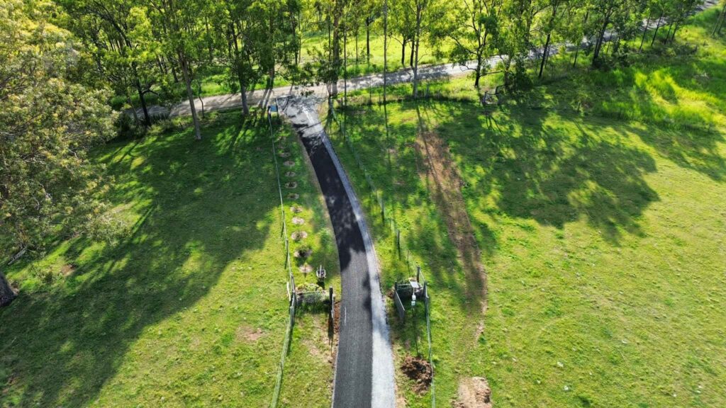Aerial view of a newly paved walkway through a grassy, tree-lined park.